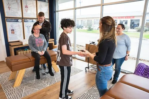 Teenager receiving chiropractic care with activator in multi-patient office