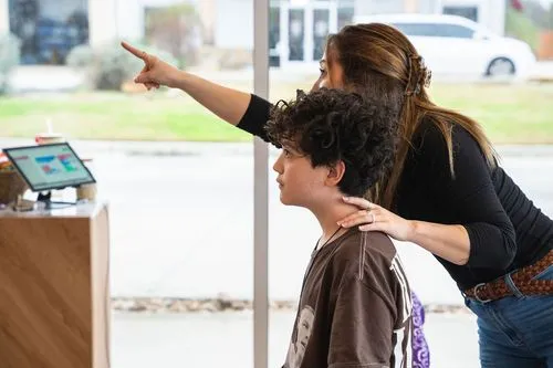 A chiropractor teaches a teenage patient.