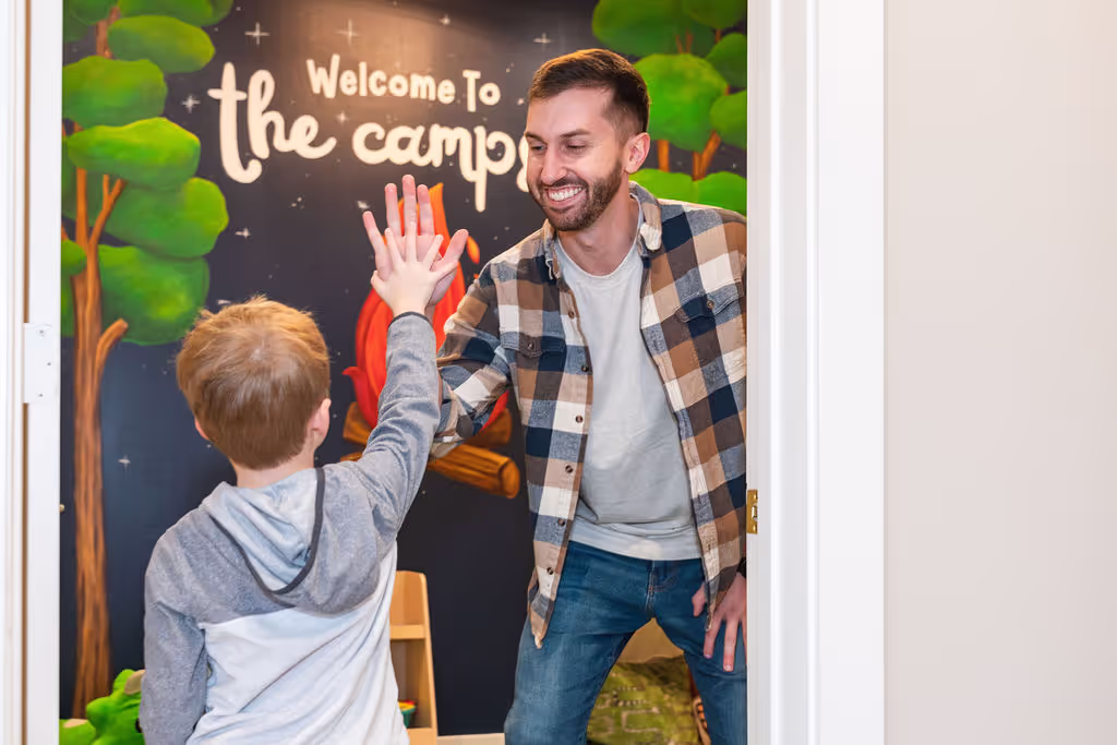A smiling employee at Ignite Chiropractic in Cypress, TX high-fiving a kid who has been adjusted to support his nervous system function.