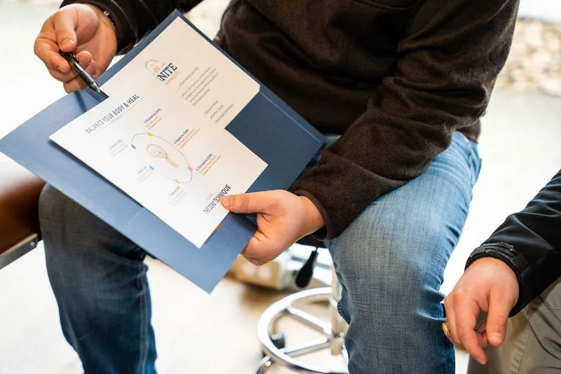 A chiropractor at Ignite Chiropractic reviewing a personalized care plan with a family, explaining how consistent chiropractic adjustments support nervous system function and overall wellness naturally.