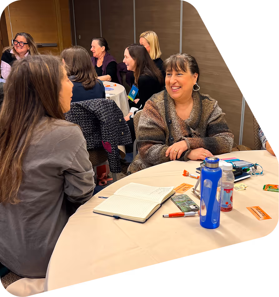 Group of women sitting around tables engaged in lively conversation during a focus group or listening session.