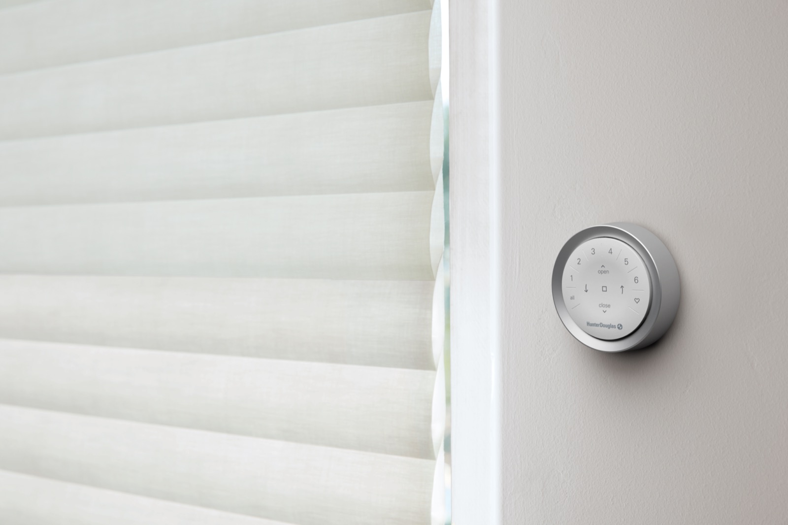 Hunter Douglas PowerView remote in a wall mount beside a sheer window shading