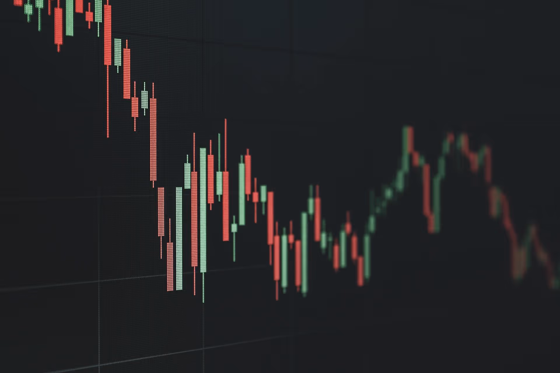 Close-up of a digital stock market candlestick chart showing fluctuating red and green prices on a dark background.