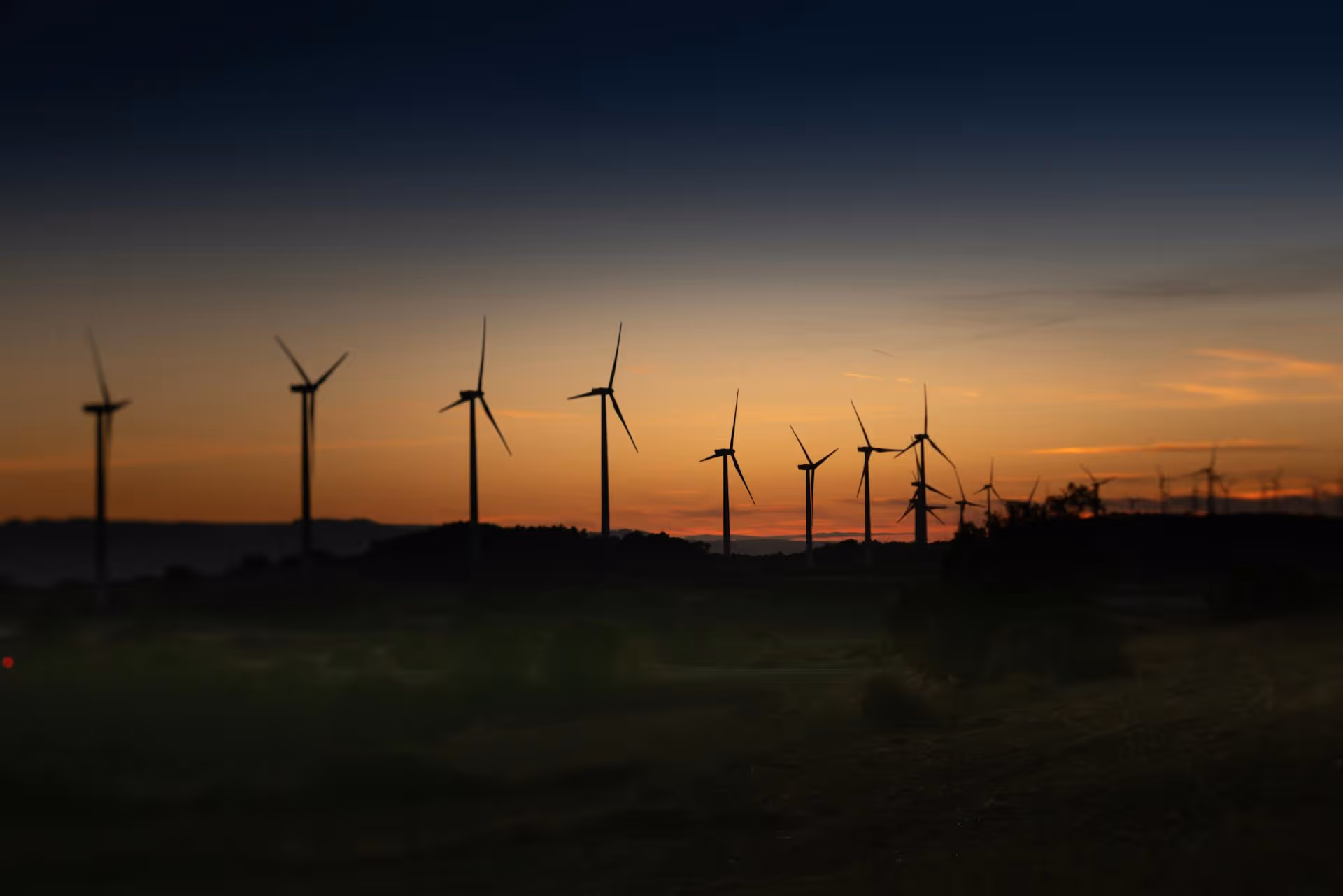 Silhouettes of multiple wind turbines against a colorful sunset sky.
