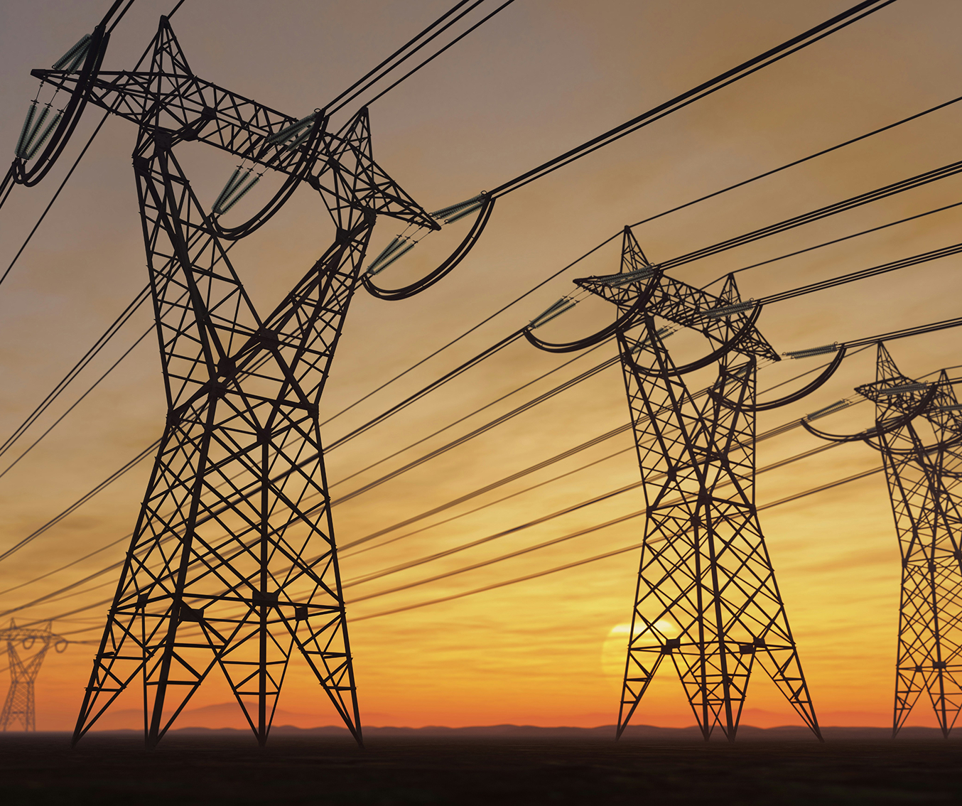 Multiple electrical transmission towers with power lines silhouetted against a sunset sky.