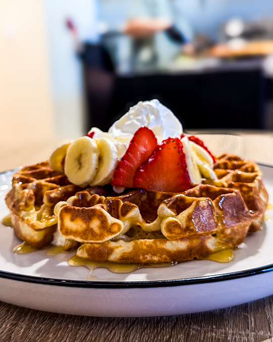 Golden breakfast waffle with fresh strawberries and blueberries