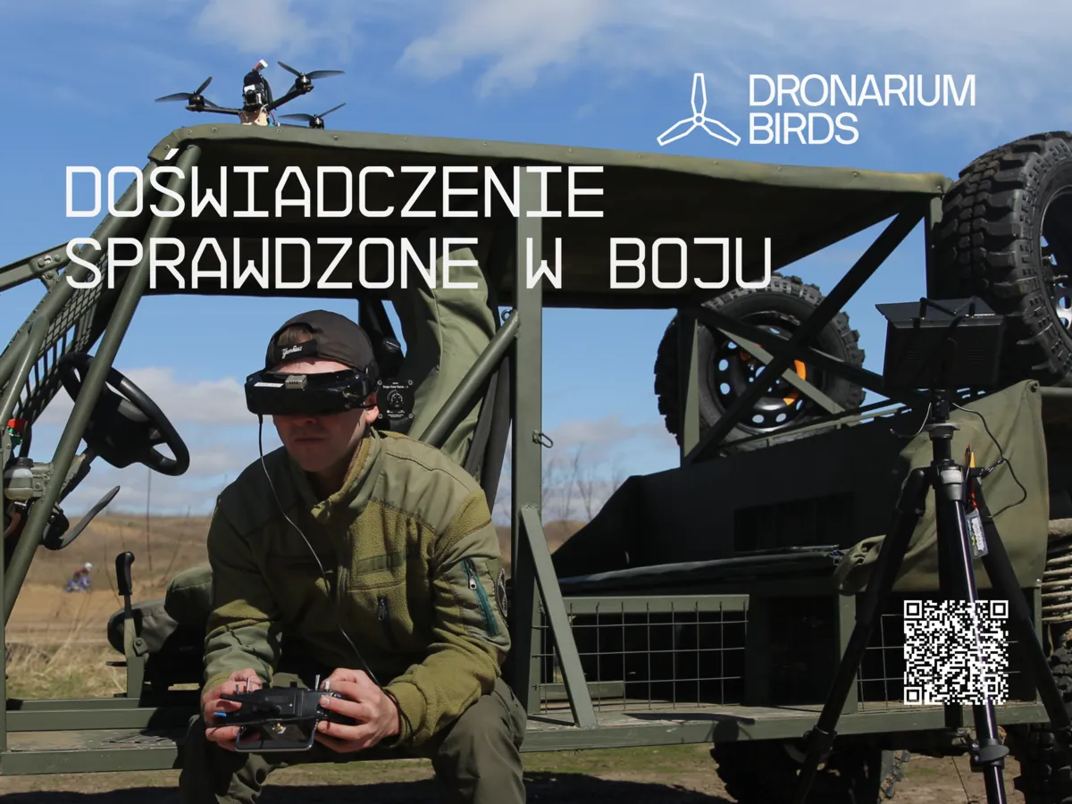 Mężczyzna w wojskowym mundurze i czapce, obsługujący drona za pomocą pilota i gogli VR, siedzący przy wojskowym pojeździe terenowym z dronem na dachu.