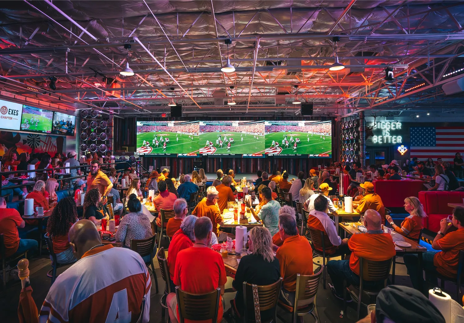 Packed sports bar crowd watching a game on large screens