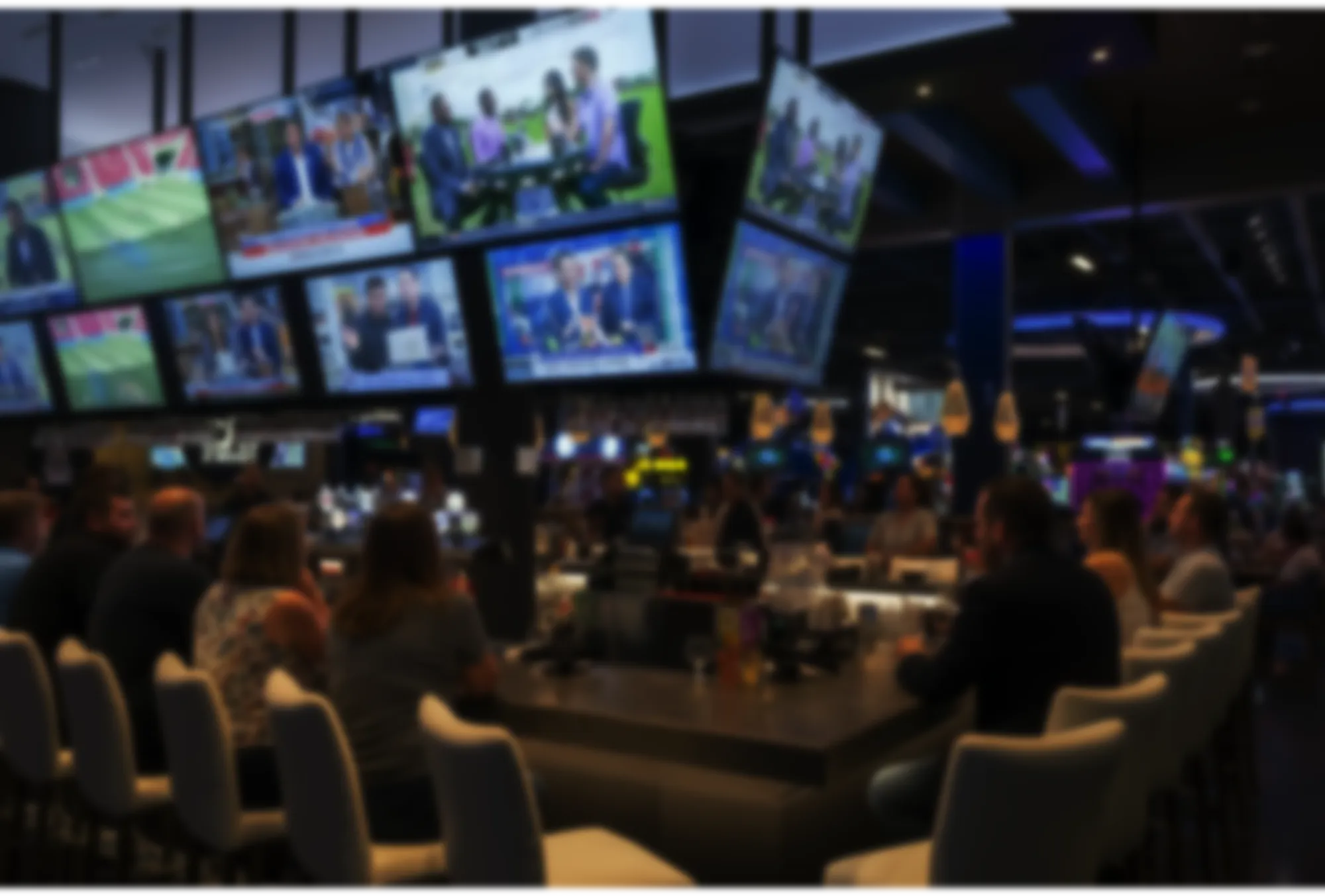 Venue interior with a wall of TVs above the bar