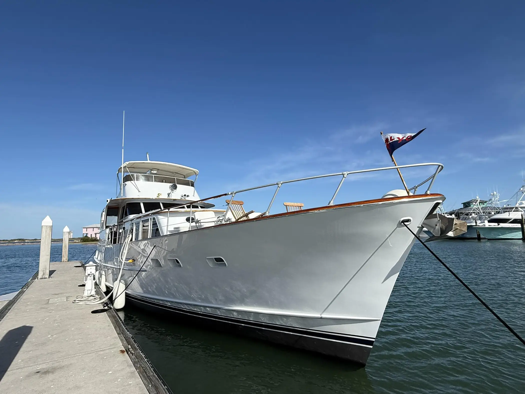 White motor yacht docked at a marina under a clear blue sky.