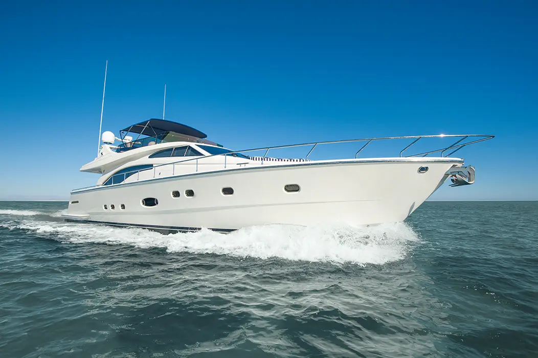 White luxury motor yacht cruising on calm sea under clear blue sky.