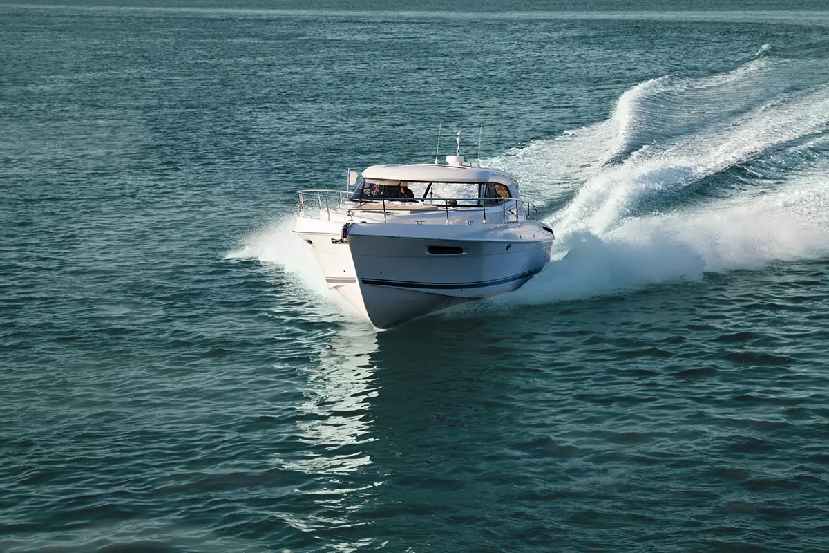 White motorboat speeding on blue water, creating wake and splashes.