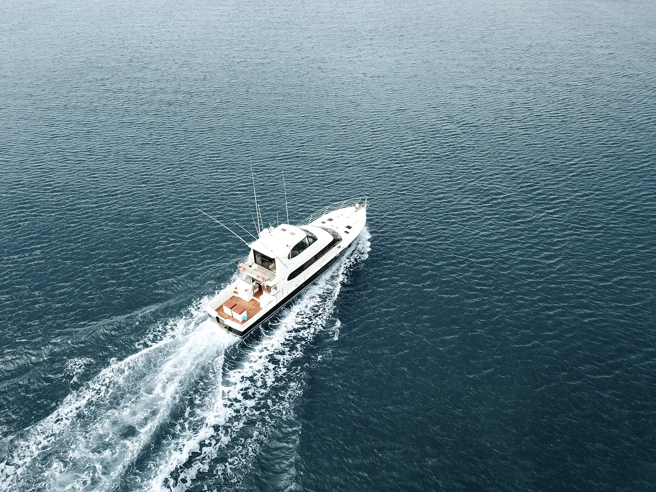 White motorboat cruising on calm dark blue water, leaving a wake behind.