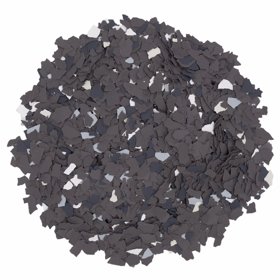 Circular pile of irregular black and dark gray flakes on a white background.