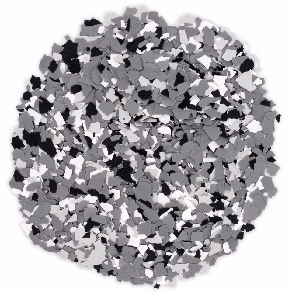 Round pile of black, white, and gray irregular plastic flakes on a white background.