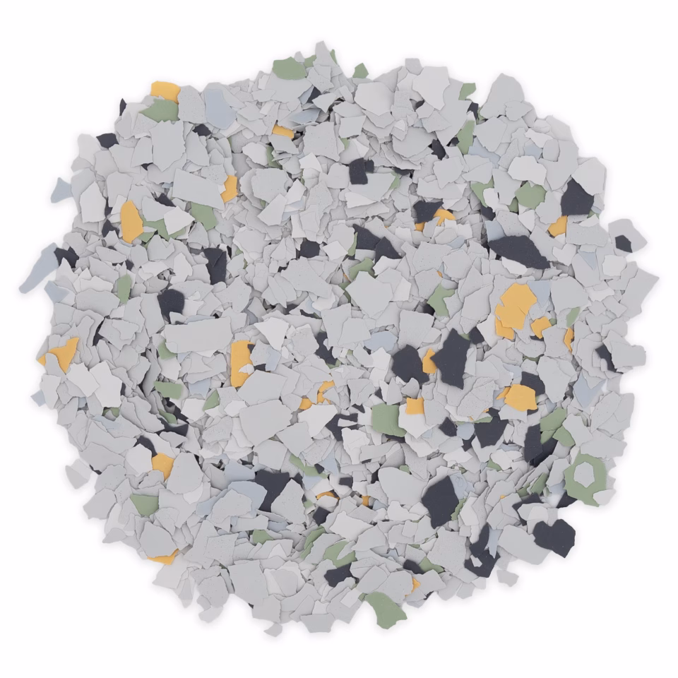 Pile of small, irregularly shaped paint flakes in gray, black, green, and yellow colors on a white background.