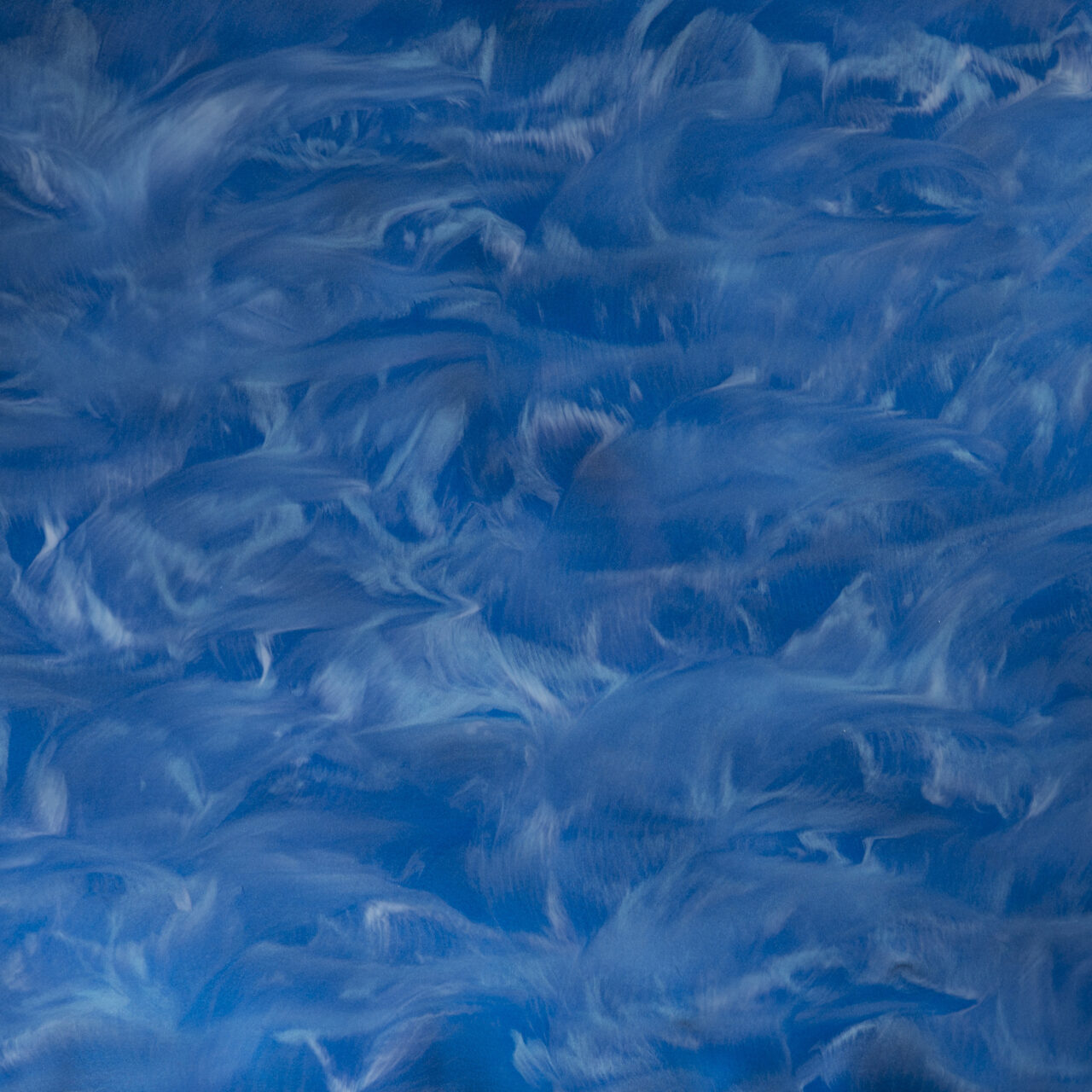 Pile of dark blue and navy small irregular flakes on white background.