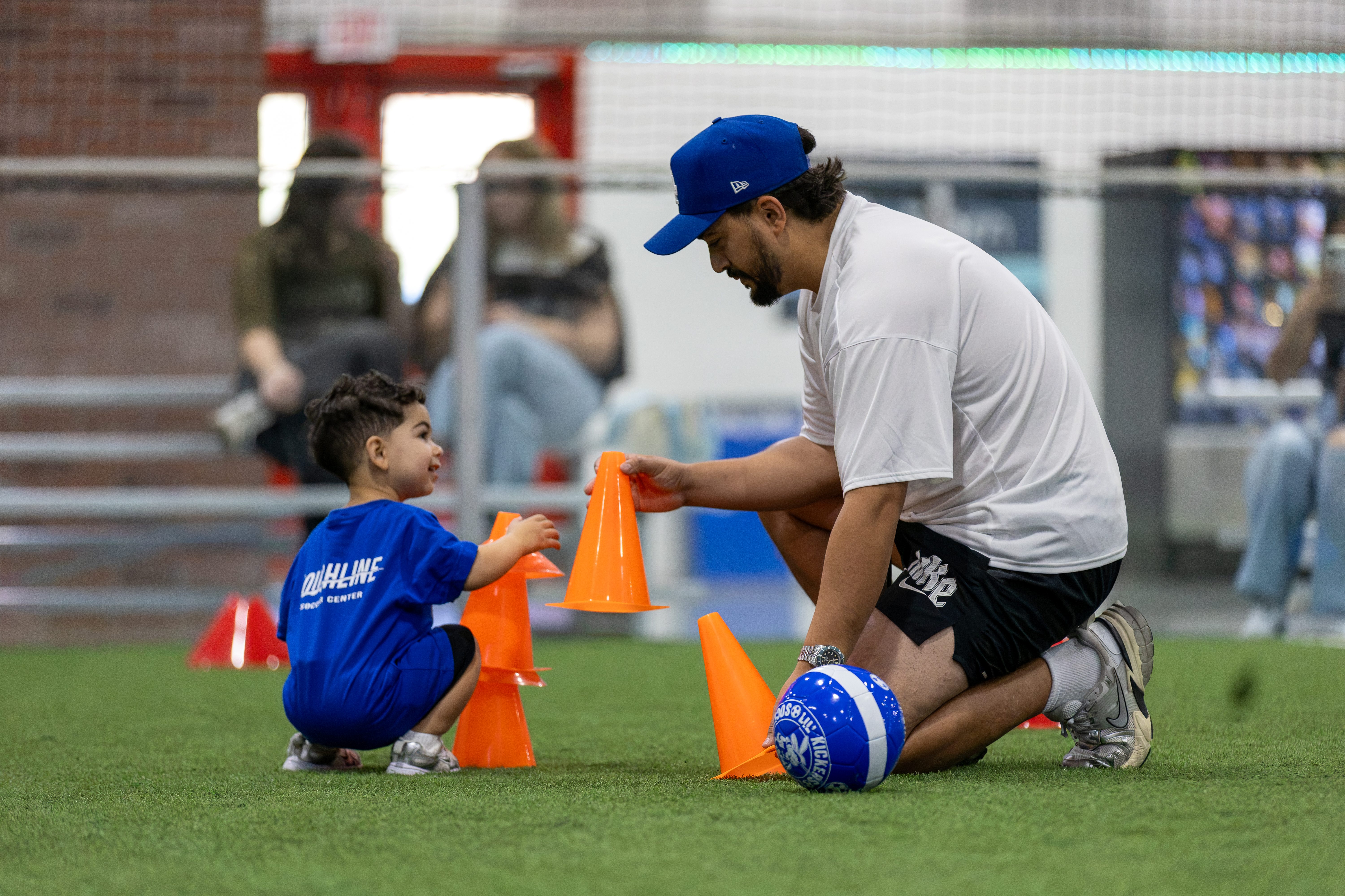 A coach high-fiving a young player beside a row of cones