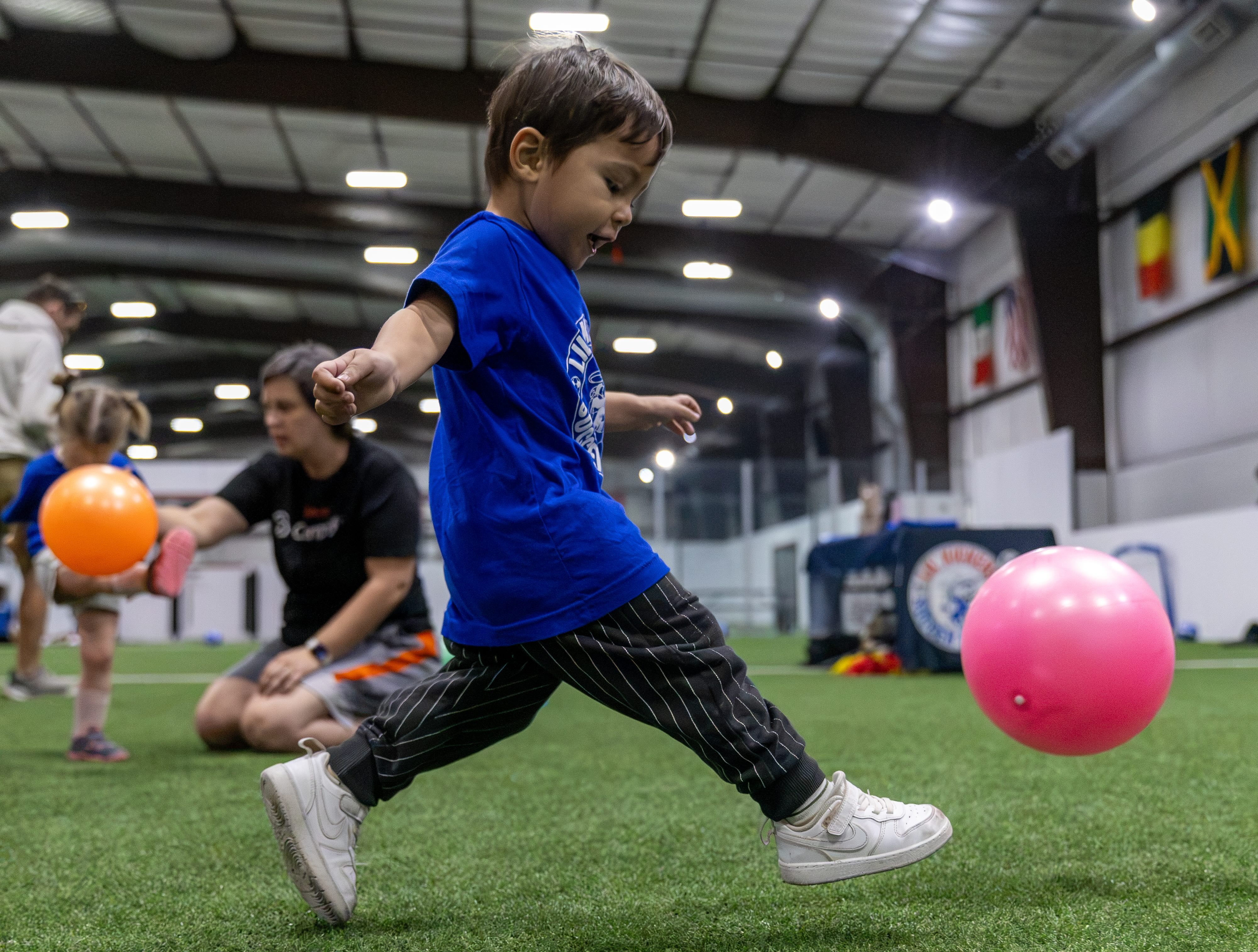 A young camper kicking a ball with colorful balls flying around