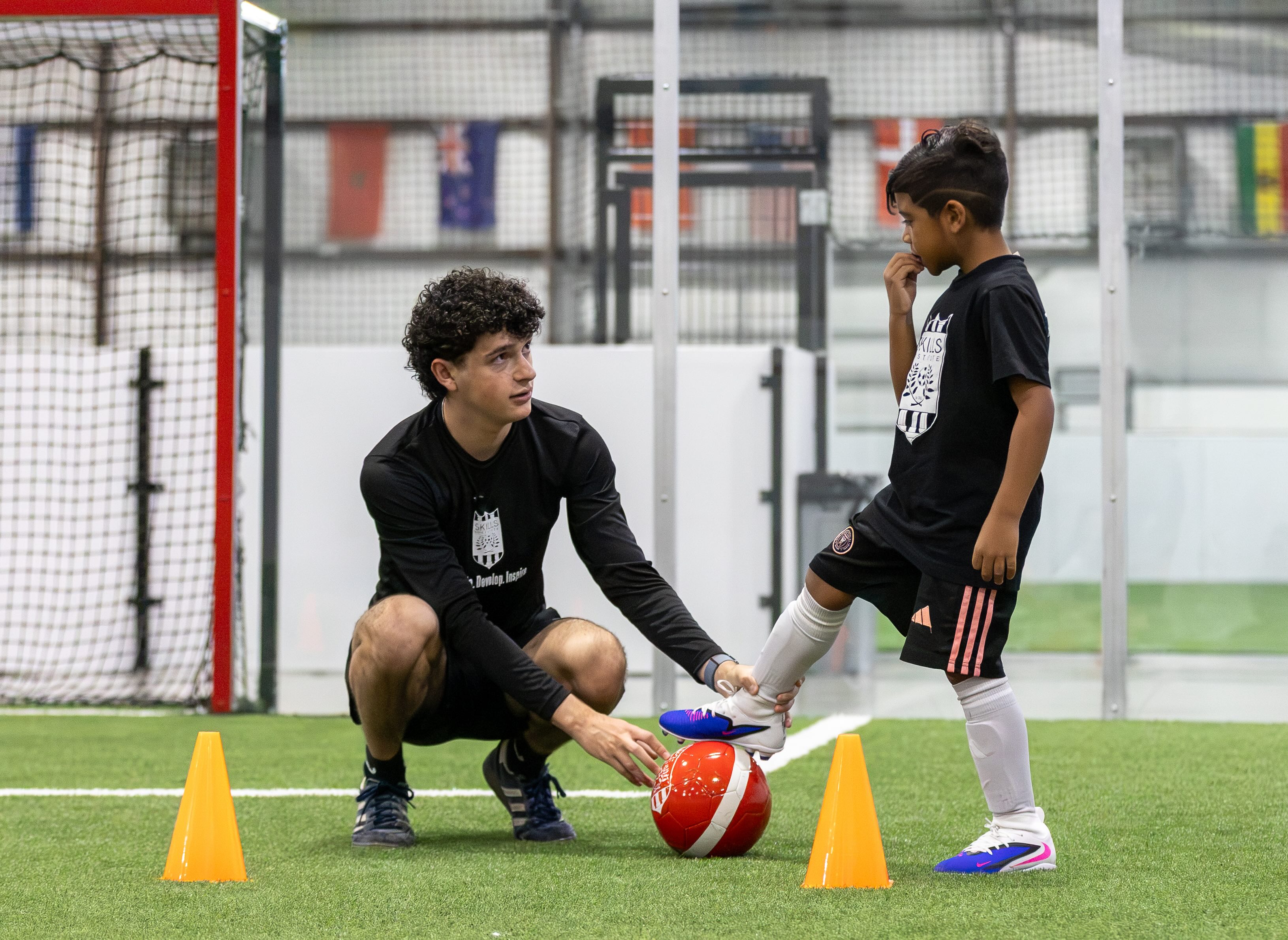A coach kneeling to give a young player one-on-one instruction