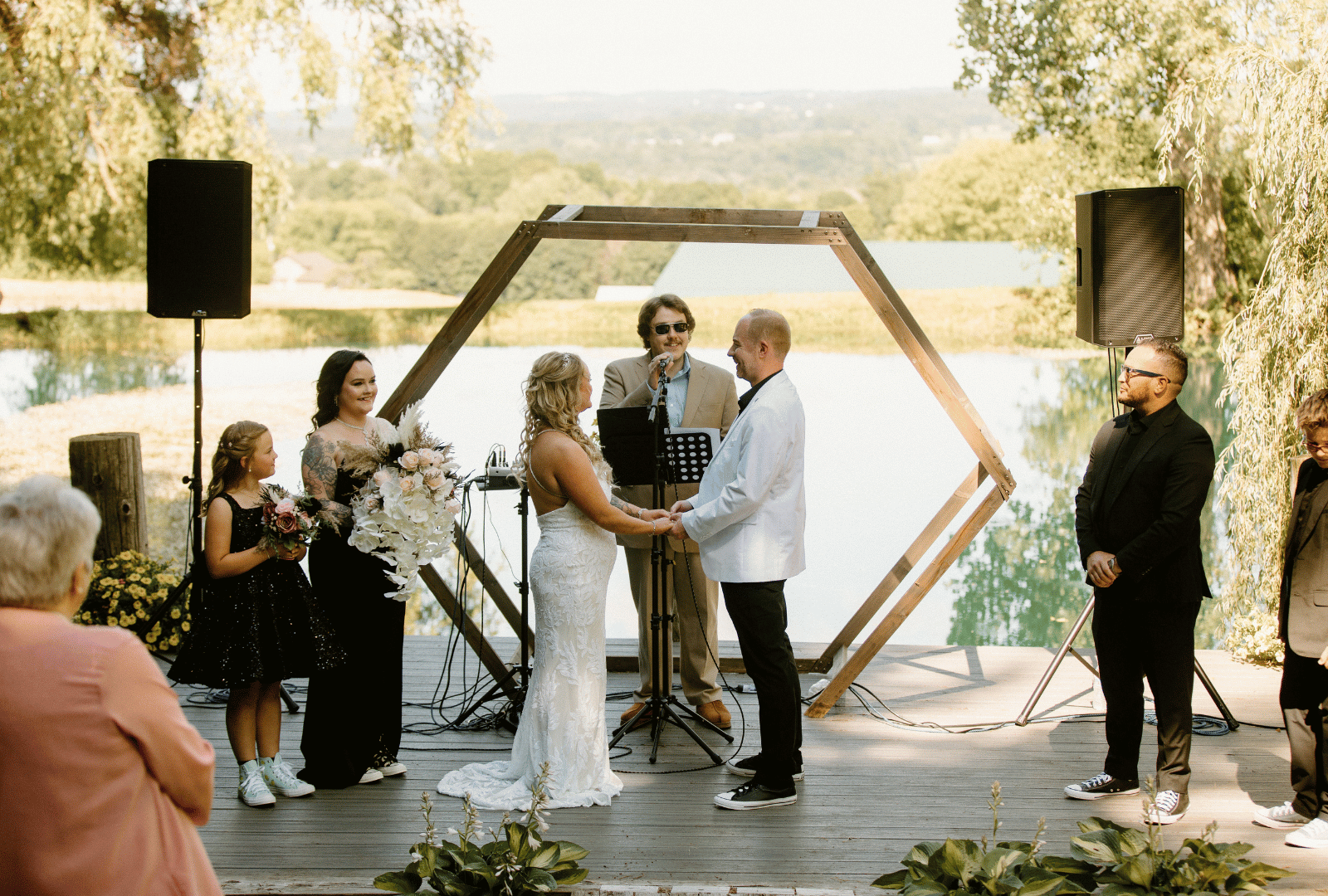 Bride and groom exchanging vows under a wooden ceremony arch at a private pond wedding venue in New York