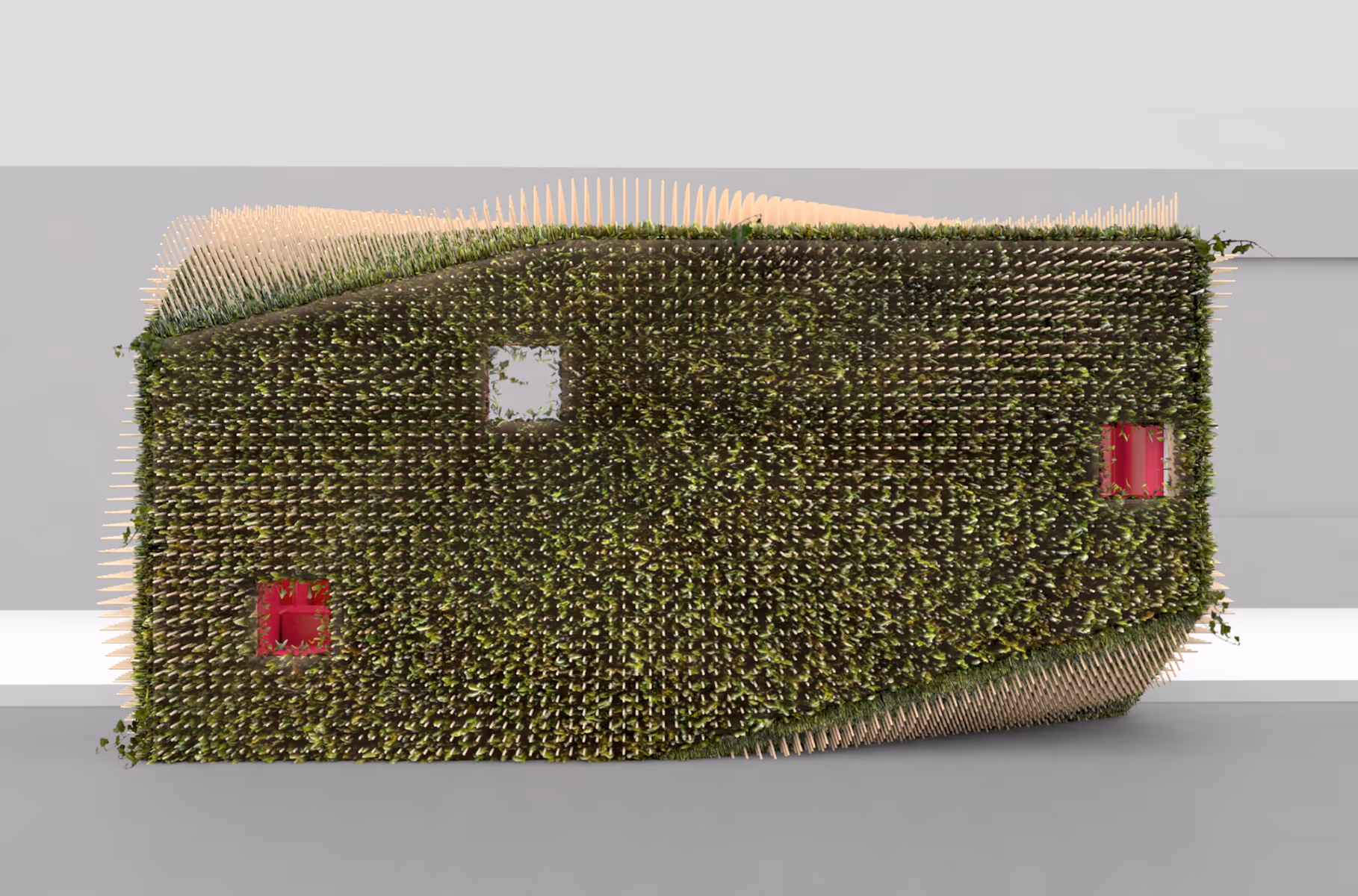 Top view of a green, spiky rectangular sculpture with red and white square cutouts indoors.