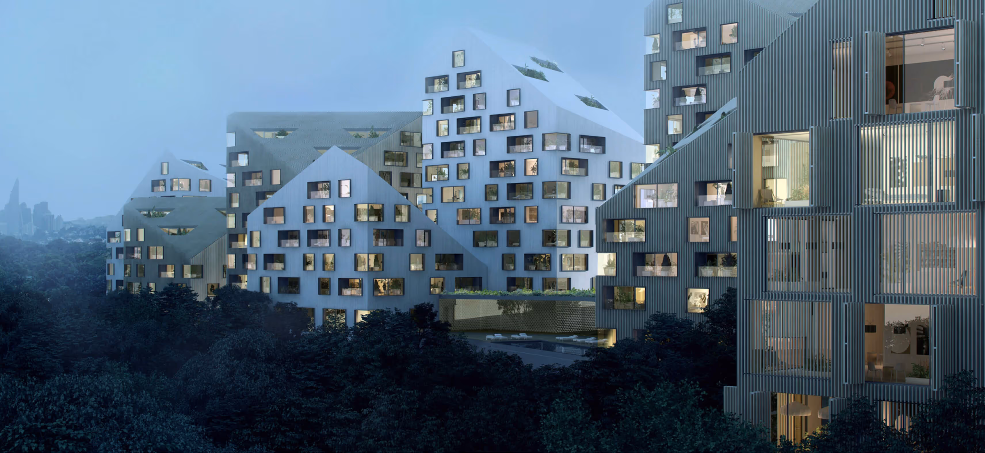 Modern residential buildings with rooftop greenery set against a forested area at dusk.