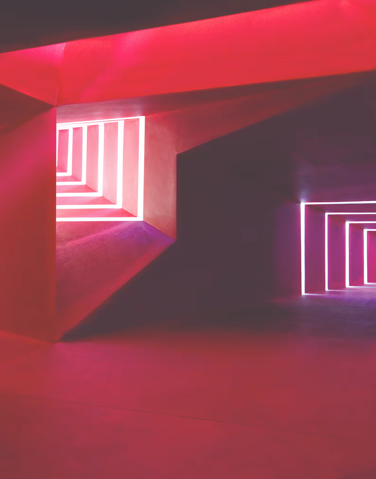 Interior space with pink and purple neon rectangular lights creating geometric patterns on walls.