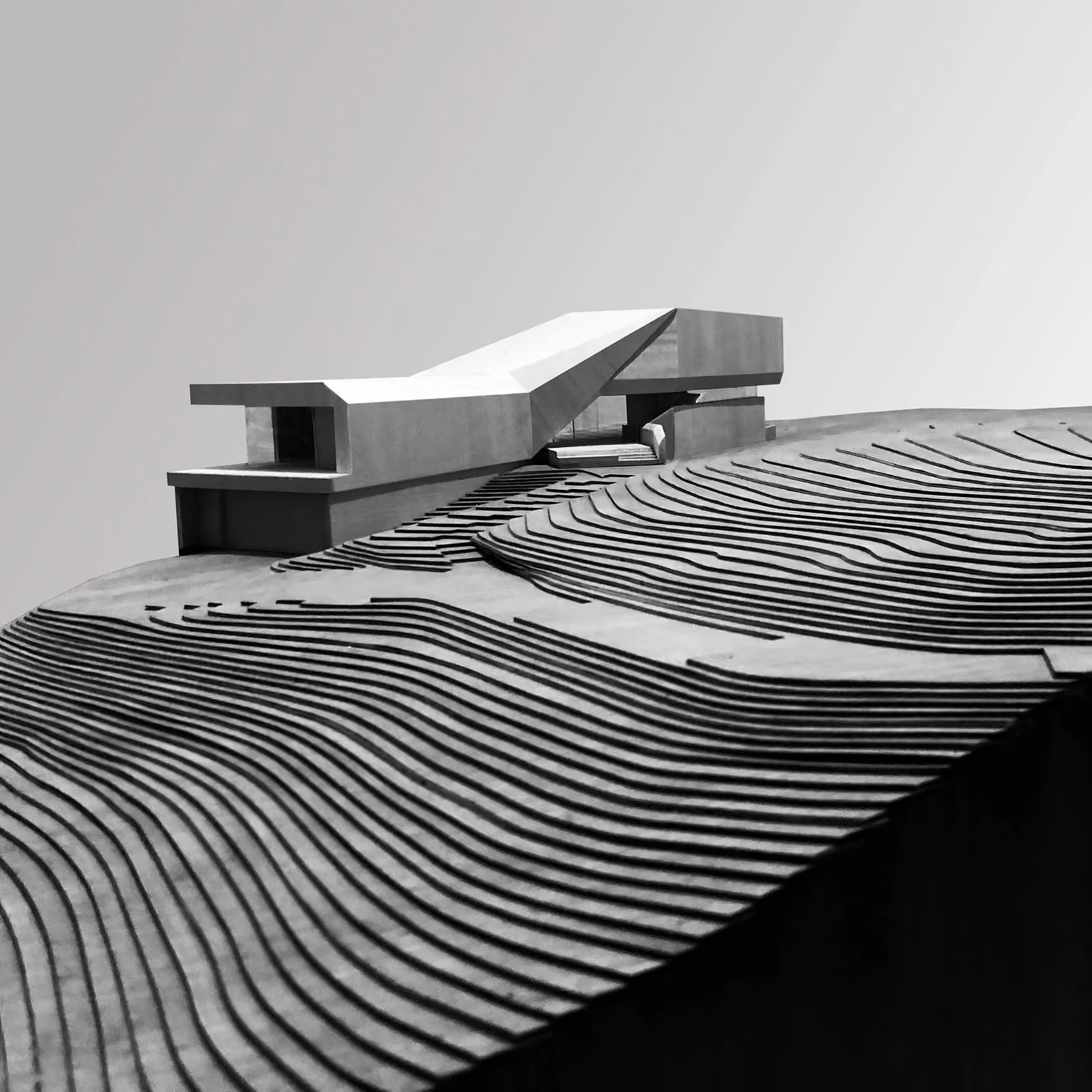 Architectural model of a modern building on tiered landscape contours.