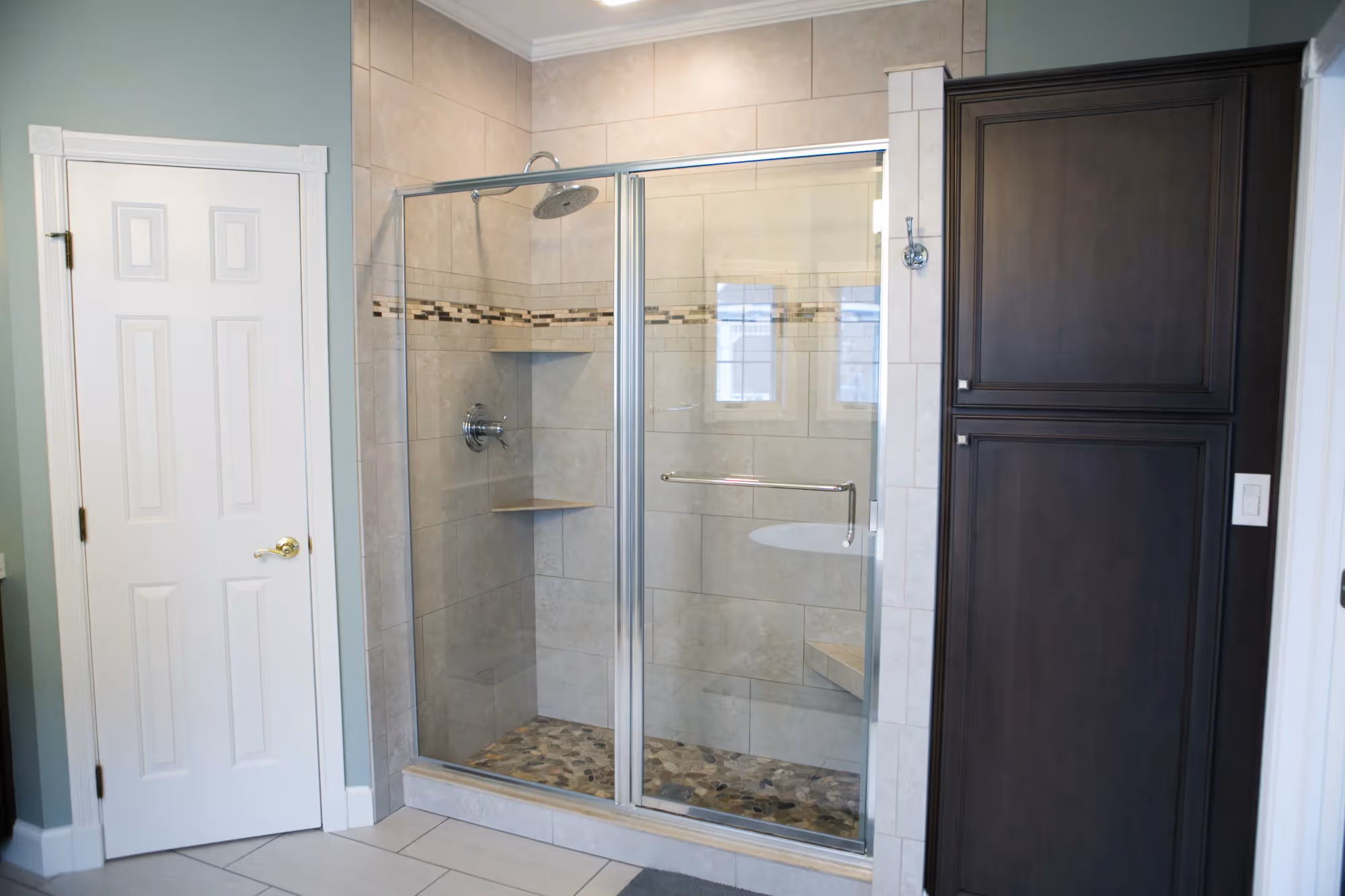 Modern shower area with glass doors and tiled walls.