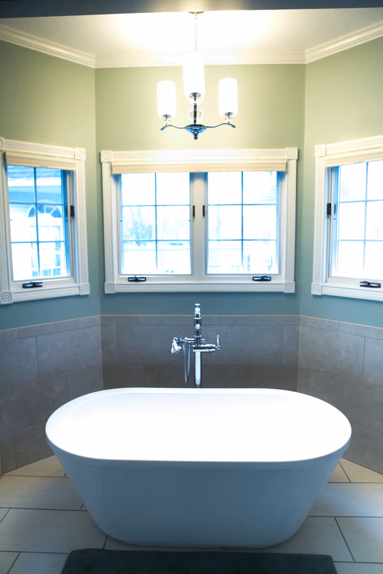 Bathroom with a bathtub under large windows.