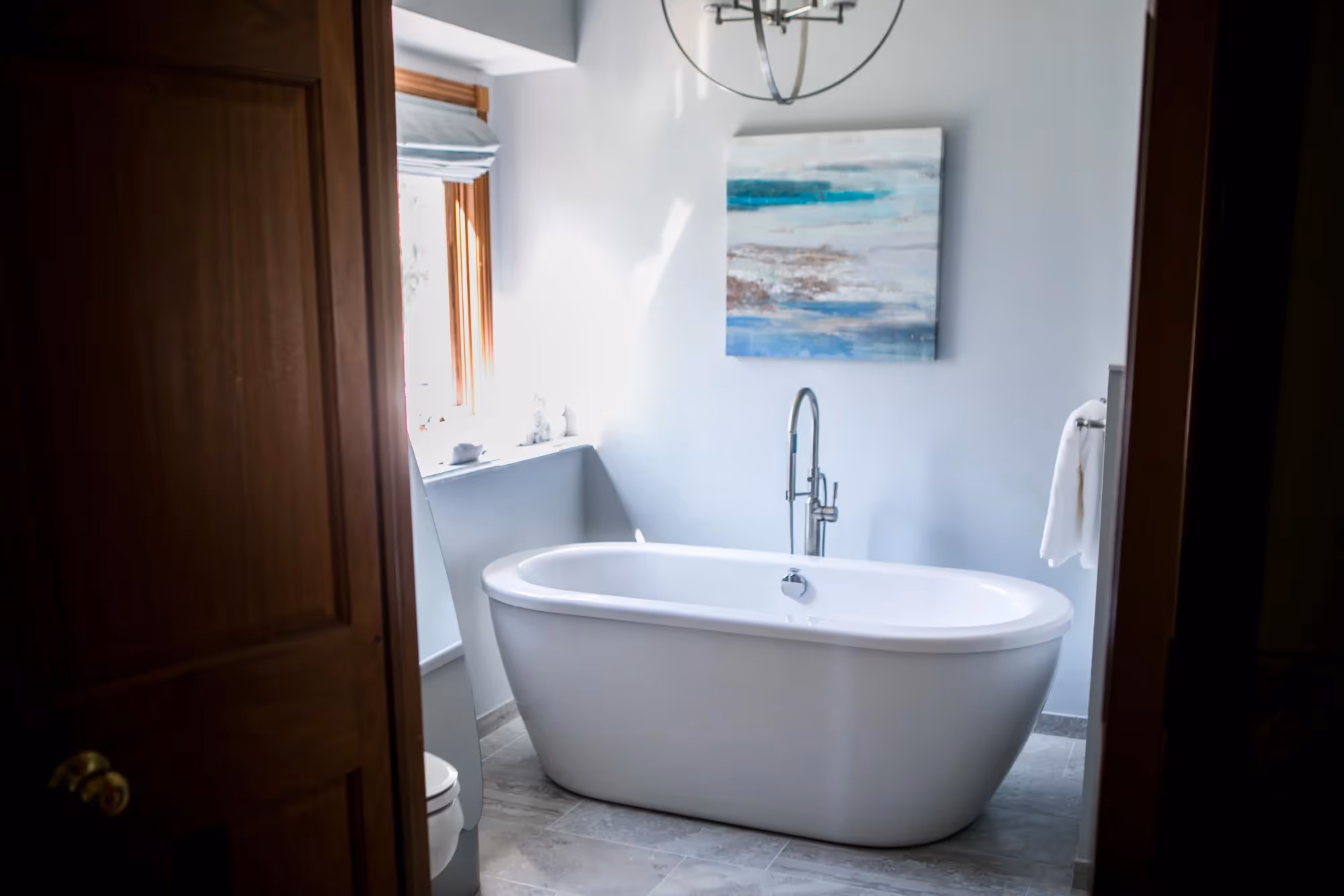 Elegant bathroom with standalone bathtub and wall art.