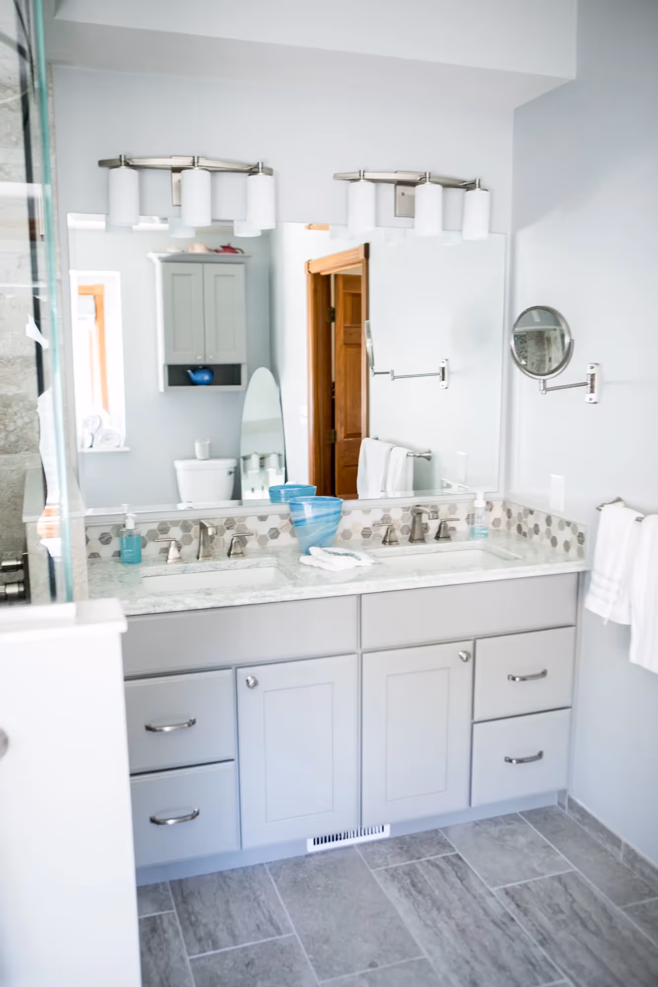 White bathroom with vanity, mirror, and tiled floor.