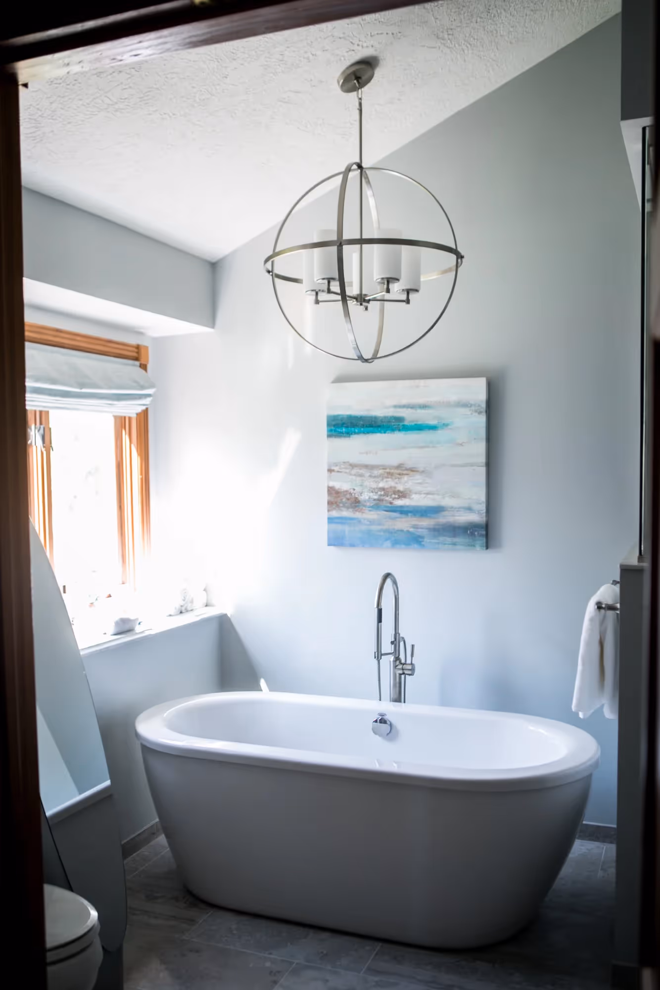 Elegant bathroom with a freestanding bathtub and chandelier.