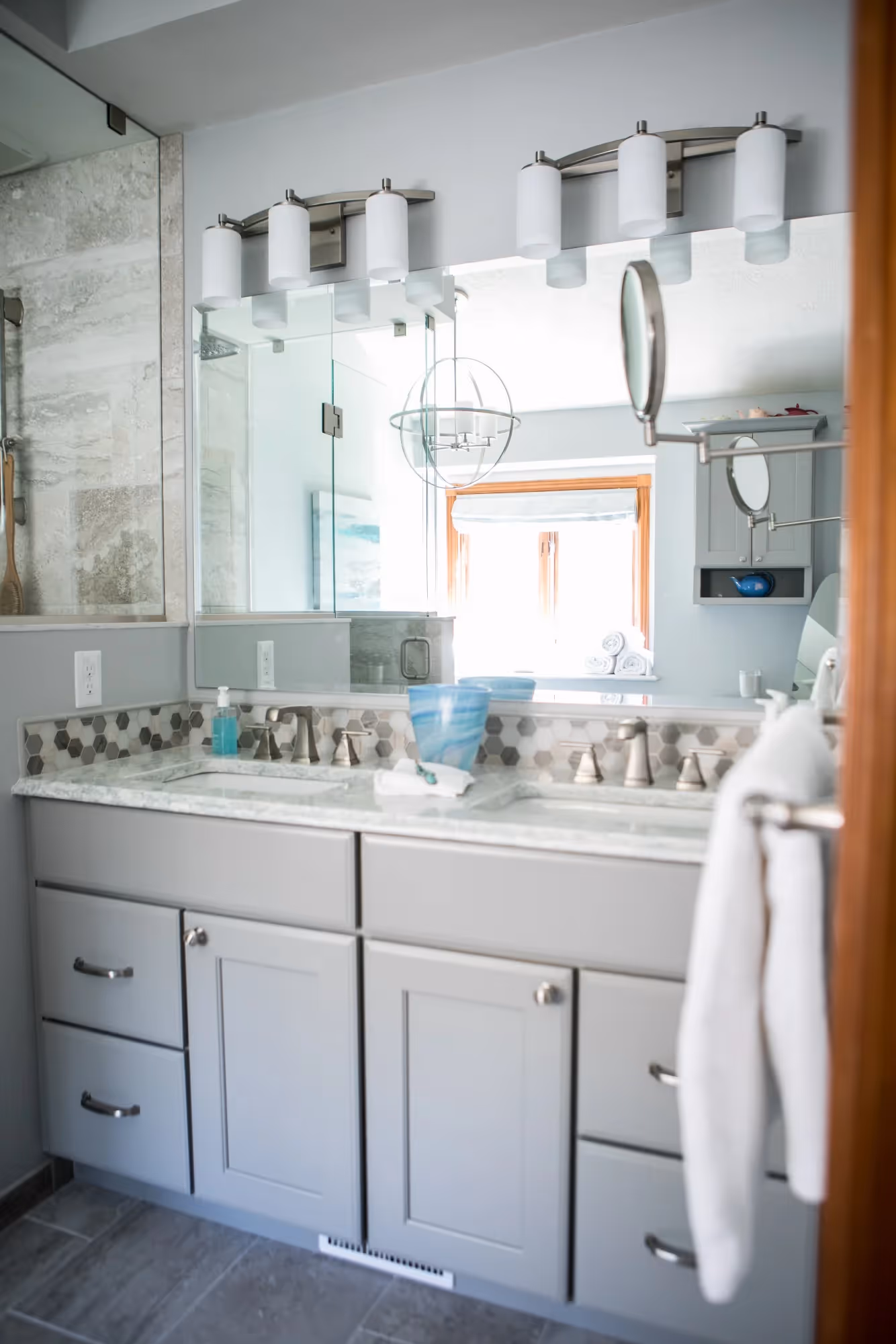 Bathroom with dual sinks, white cabinetry, and wall shelves.