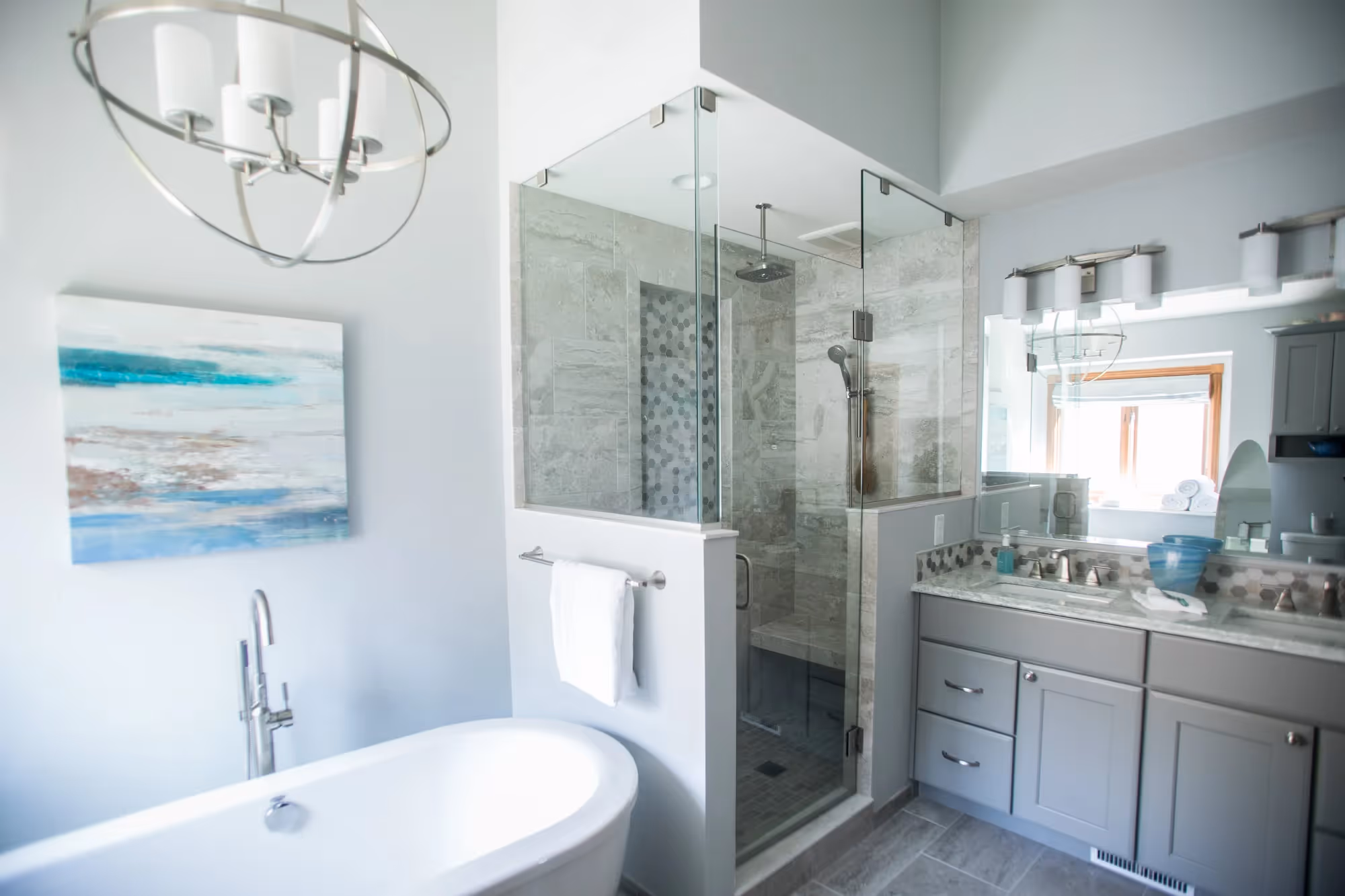 Stylish bathroom with glass shower, bathtub, and coastal-themed decor.