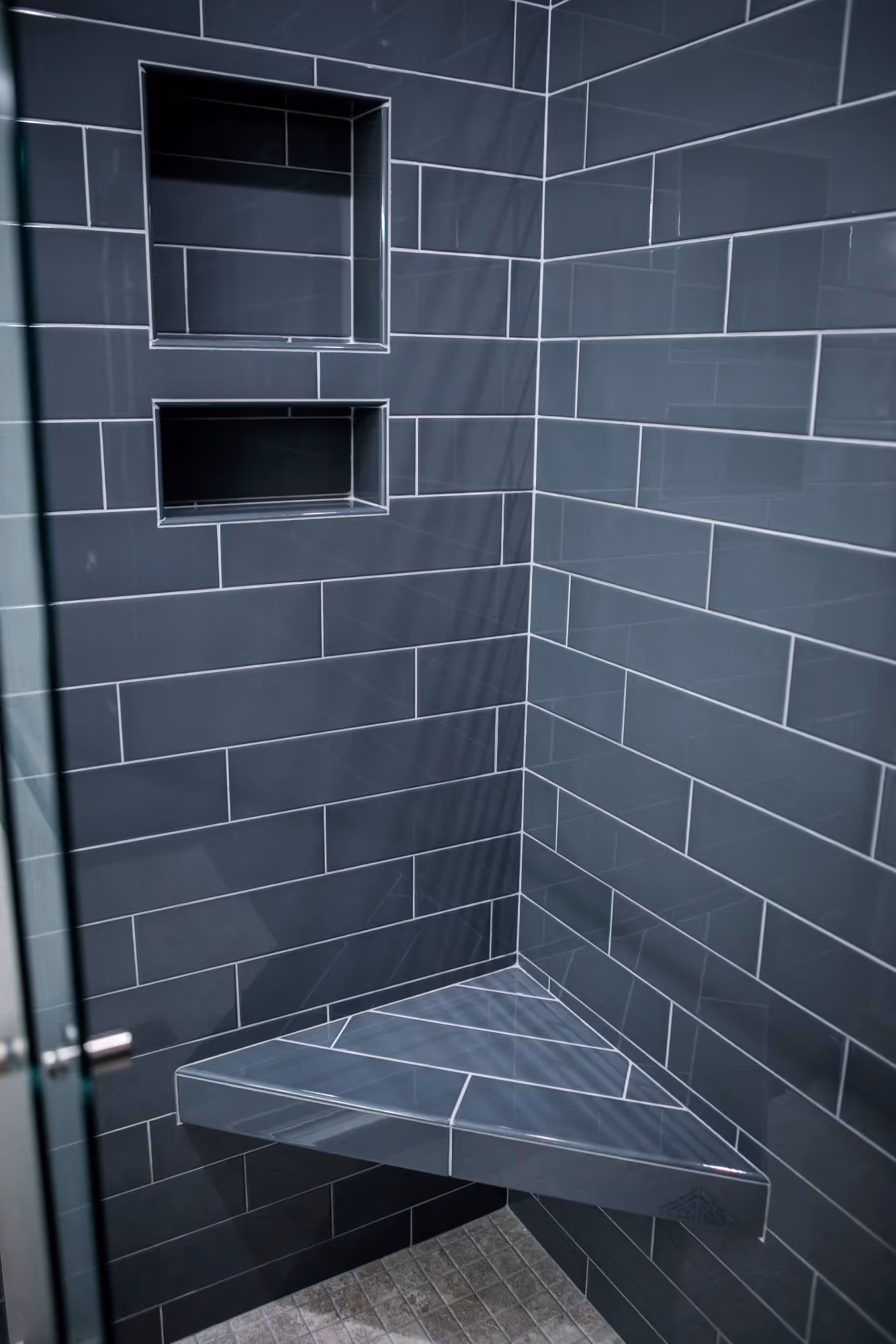 Dark tiled shower with built-in shelf.