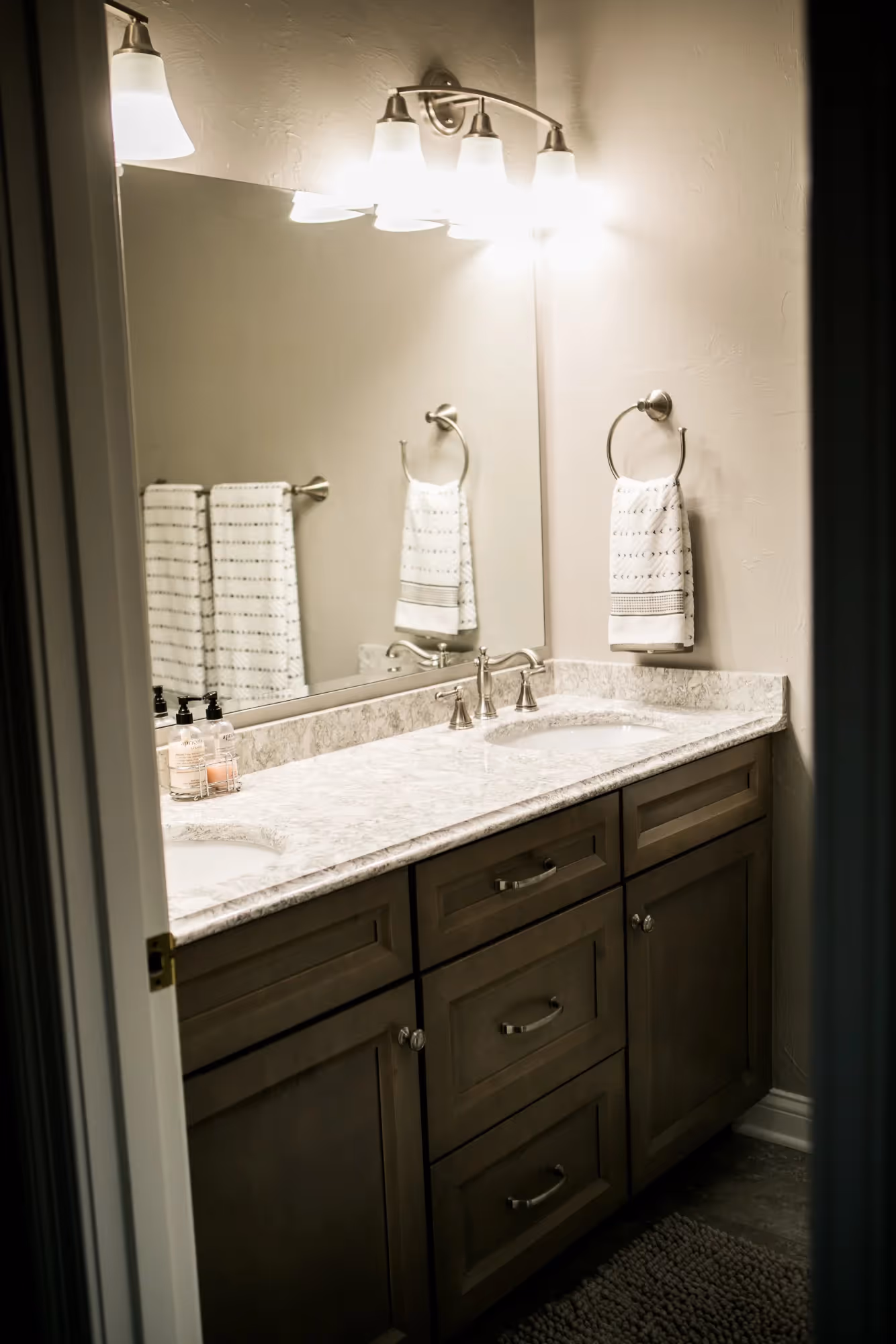 Bright bathroom with twin sinks and illuminated mirrors.