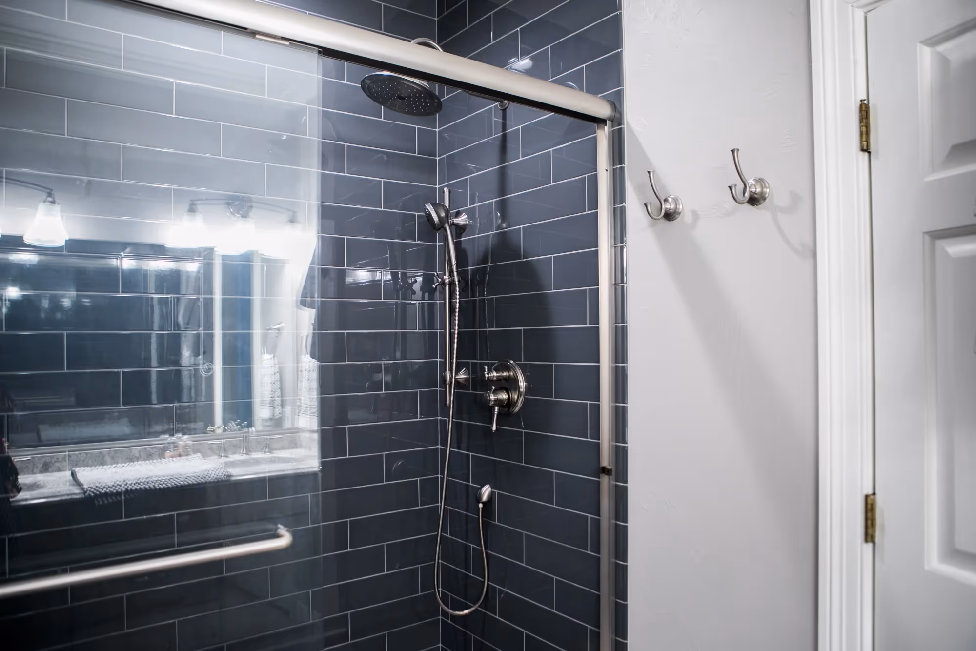 Modern shower with glass doors and dark tiles.