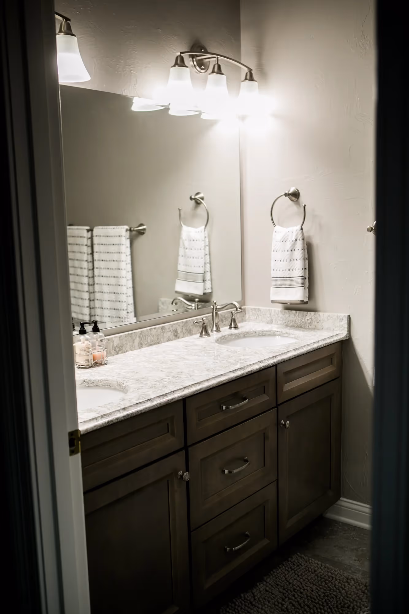 Bright bathroom with twin sinks and lights.