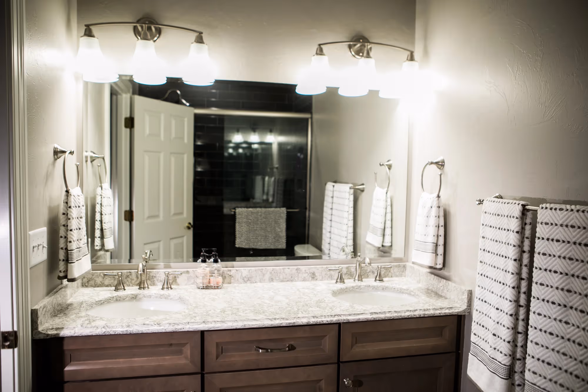 Bathroom with double sinks, mirrors, and light fixtures above.