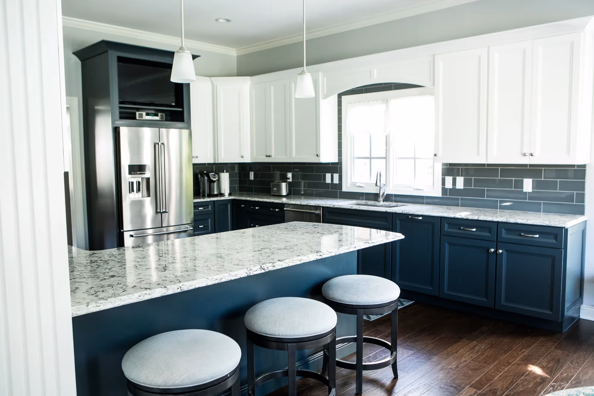 Kitchen island with bar stools and dark blue cabinets.