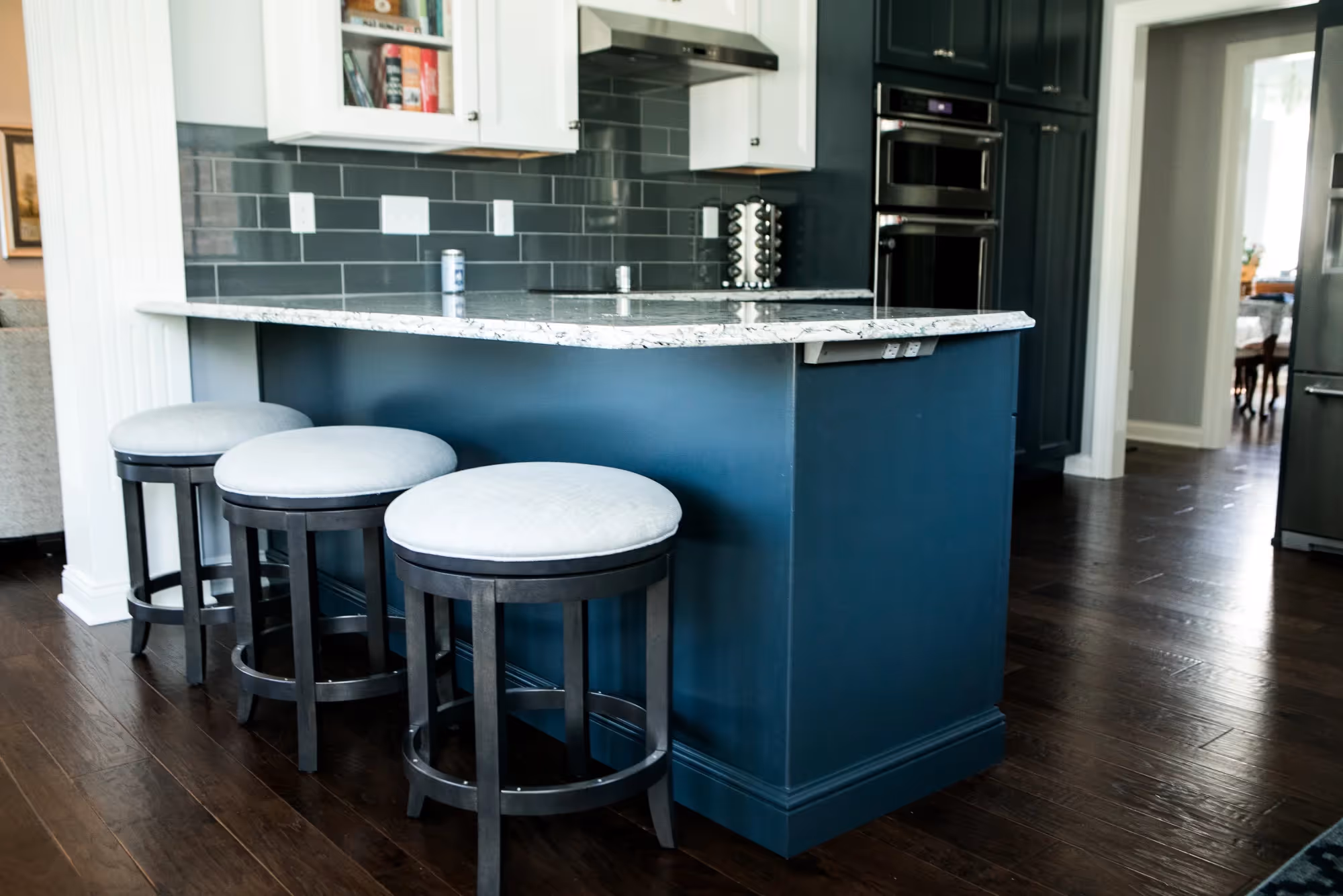 Kitchen interior with dark blue island and white bar stools