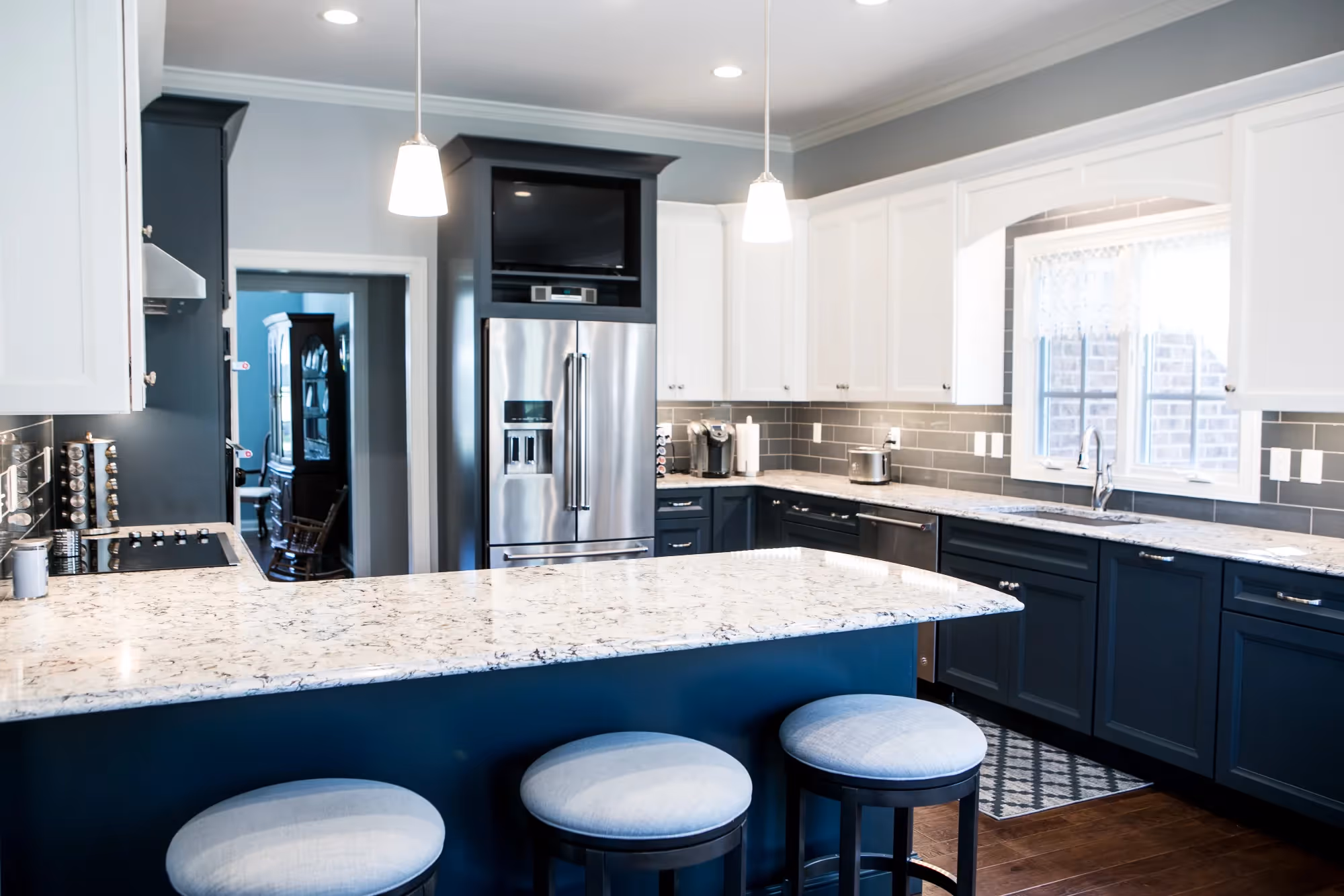 Open kitchen with island seating, gray cabinetry, and bright natural lighting.