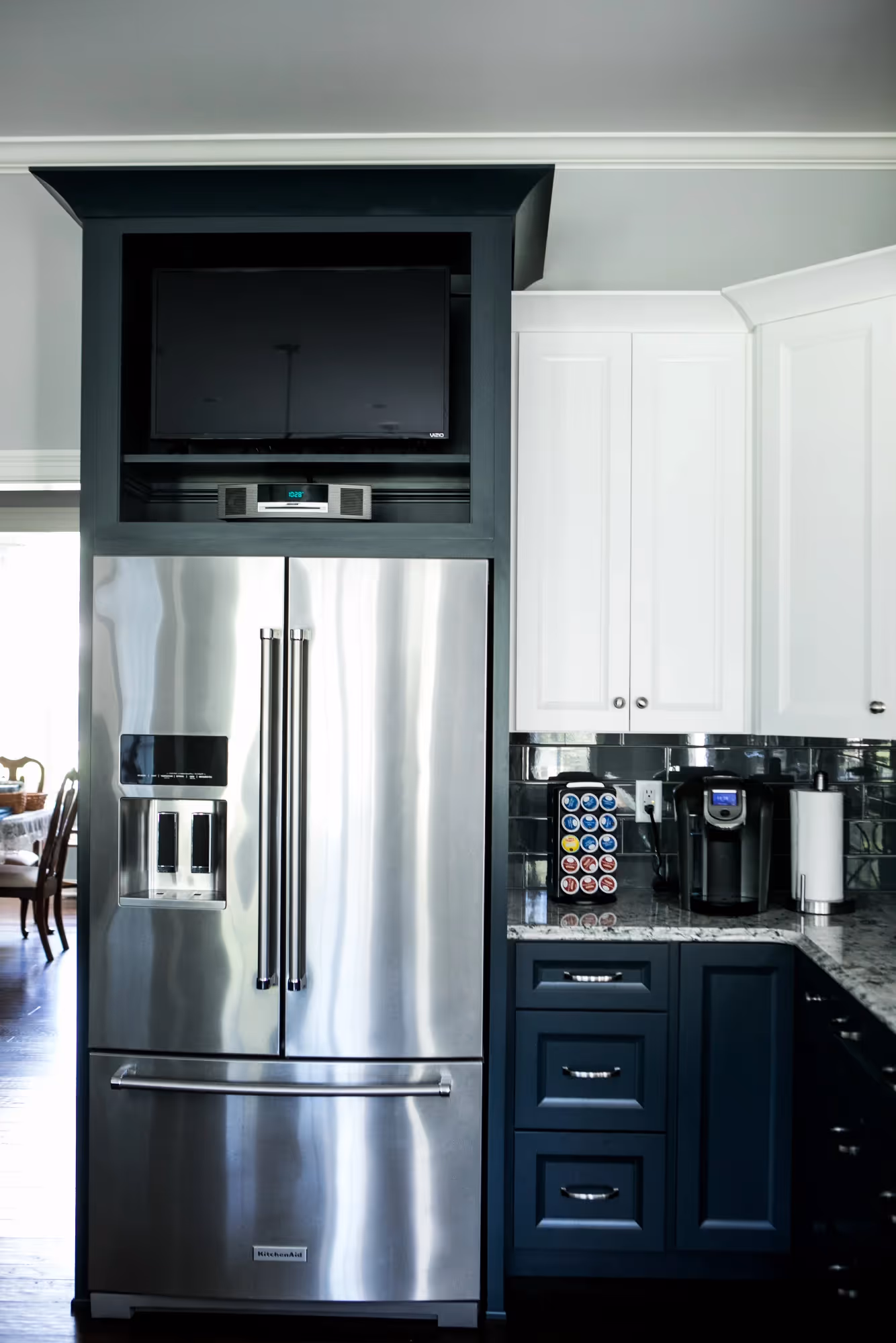 Compact modern kitchen with stainless steel refrigerator and dark cabinets.