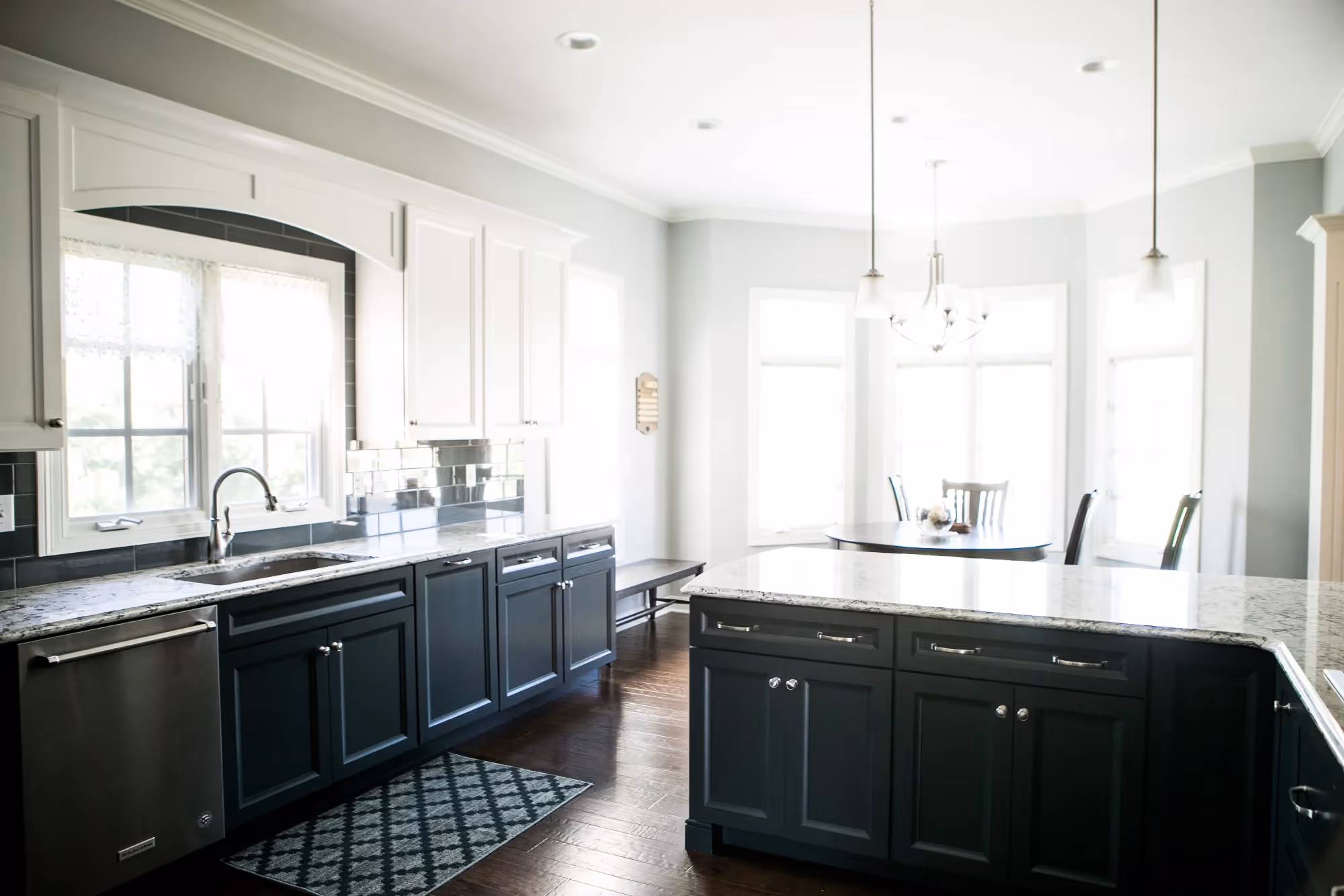 Modern kitchen filled with natural light, featuring white walls and large windows.
