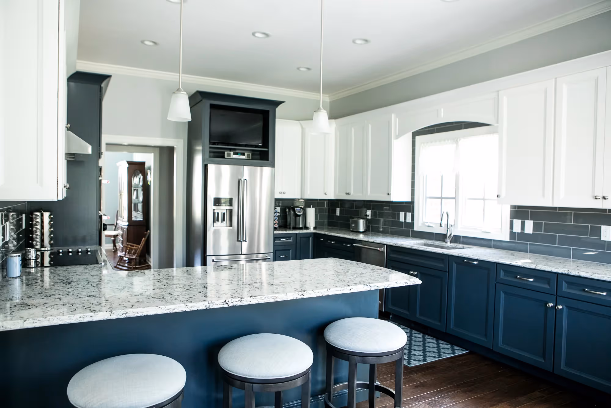 Modern kitchen with large island, white counter stools, and blue cabinetry.