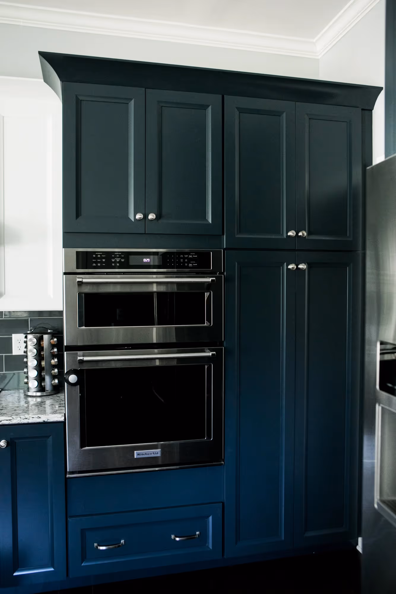 Dark blue kitchen cabinets with built-in oven and white countertop.