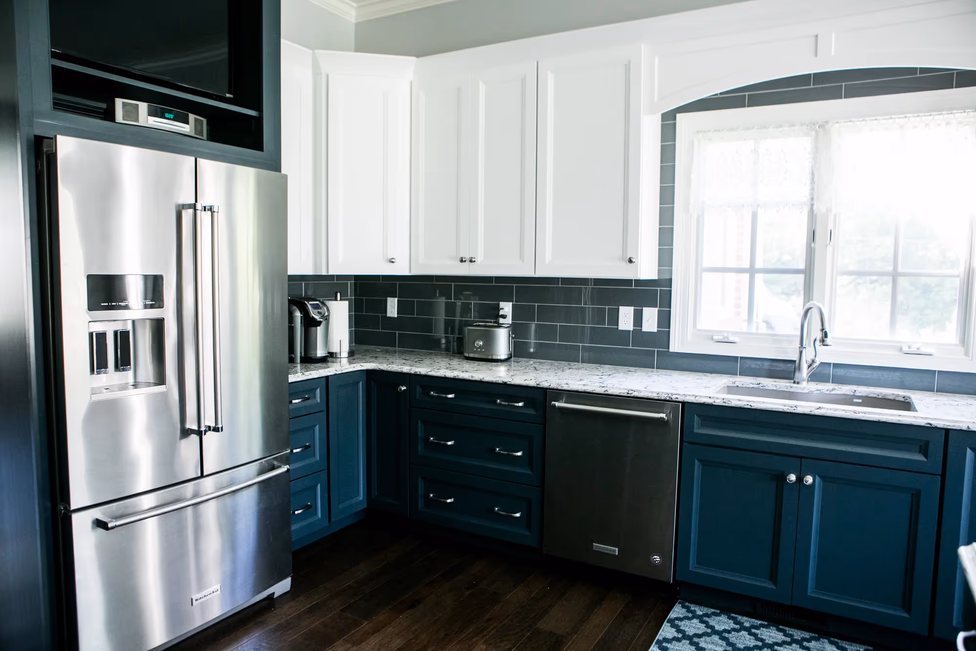 Bright kitchen with black cabinets, white walls, and multiple windows.