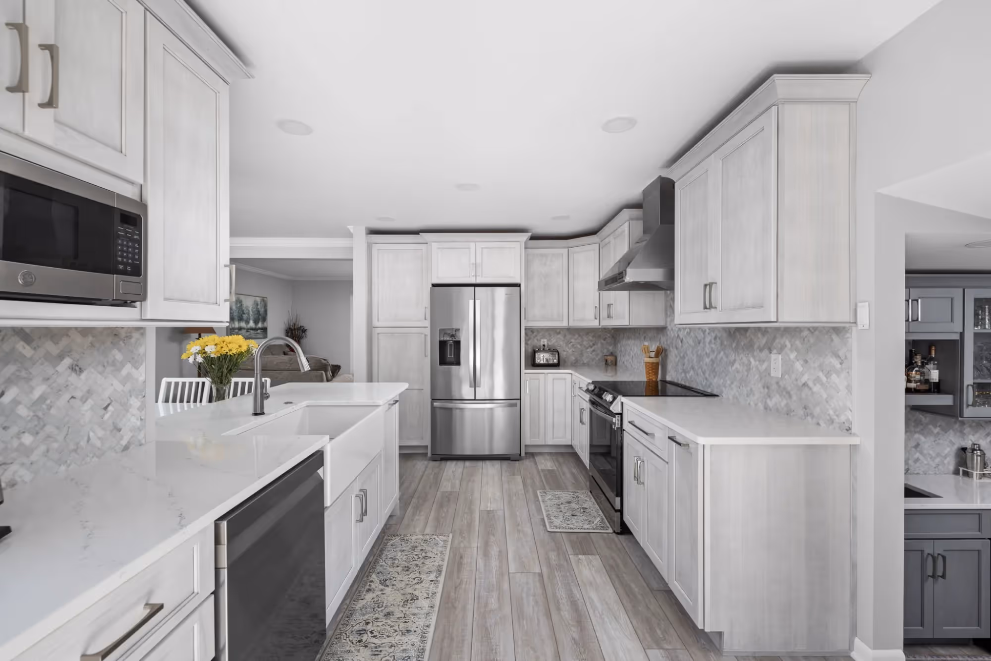 Modern white kitchen with island, pendant lighting, and wood flooring.